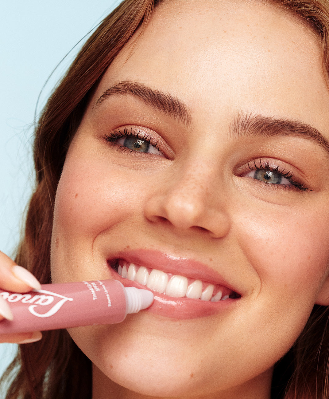 Model applying lanolips tinted lip balm in perfectly nude shade.