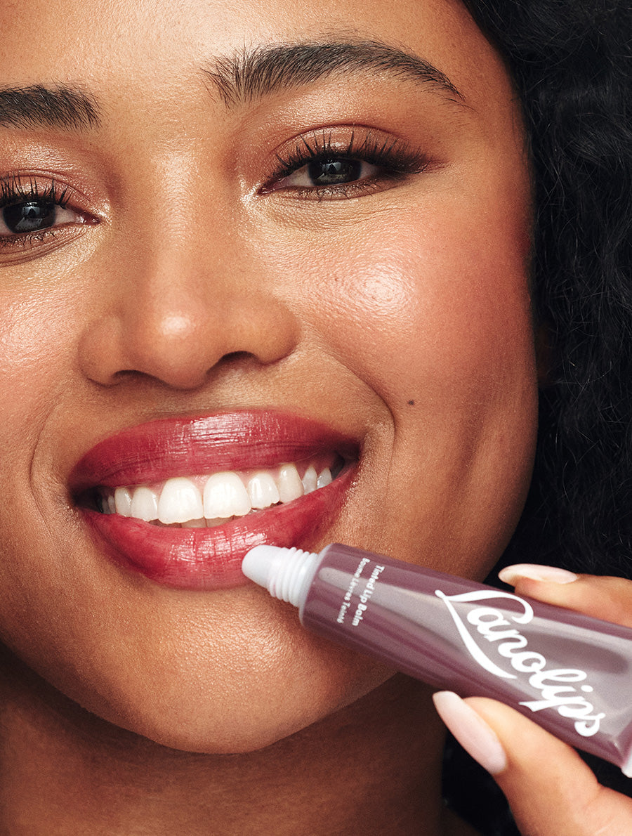 Model applying Lanolips Tinted Lip Balm Spice