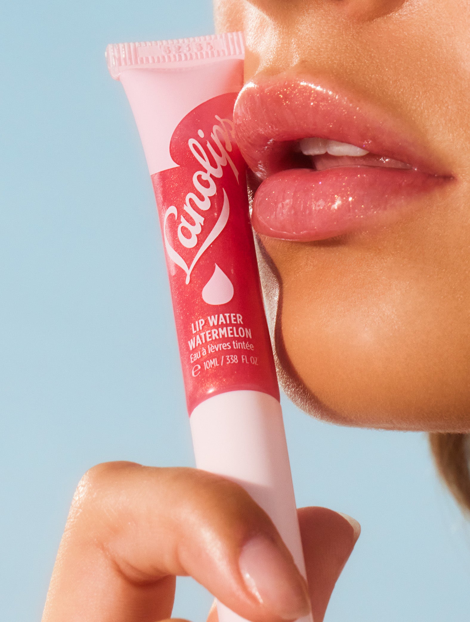 Model wearing Lanolips Lip Water Watermelon on their lips, while holding a tube against her face. Lip Water Watermelon is a sheer wash of pink shimmer that looks radiant on everyone.