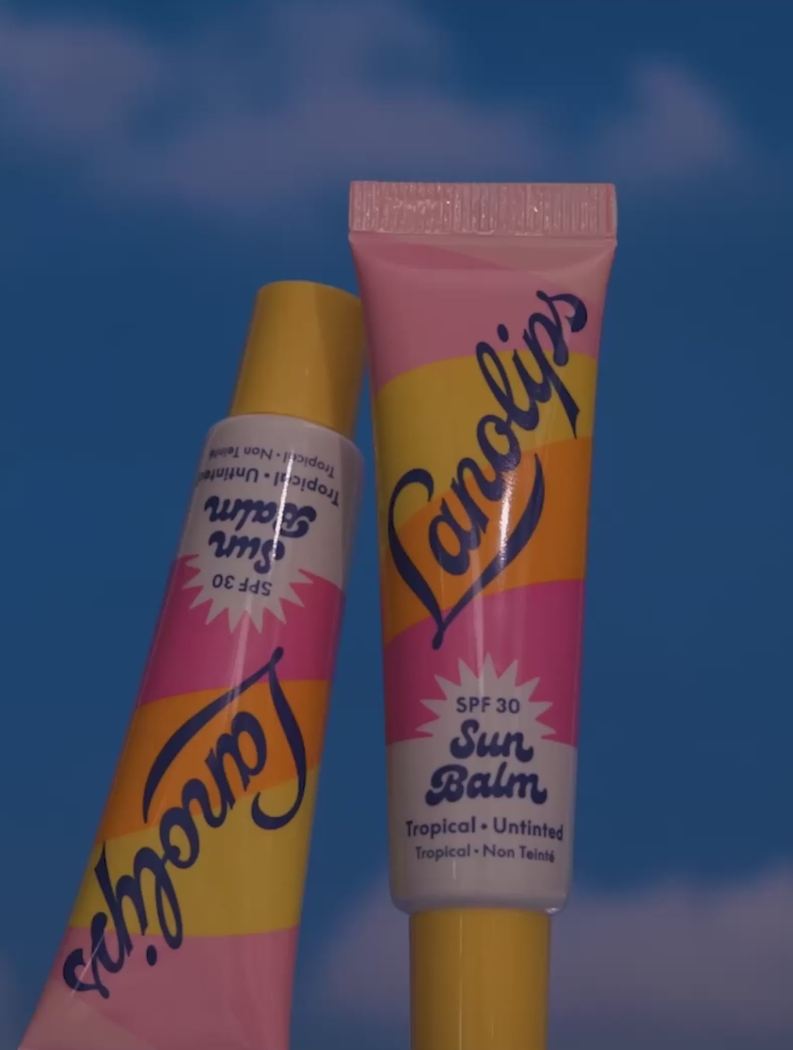 Video of the Lanolips Sun Balm SPF 30 Tropical lip balm - showing montage shots of the product, as well as the model applying the lip balm on their lips. An SPF lip balm you’ll reach for daily, tested to meet global UVA/UVB
standards. Infused with nourishing ingredients and a touch of all-natural
tropical bliss - smells like island oils, sunscreen, and pineapple.