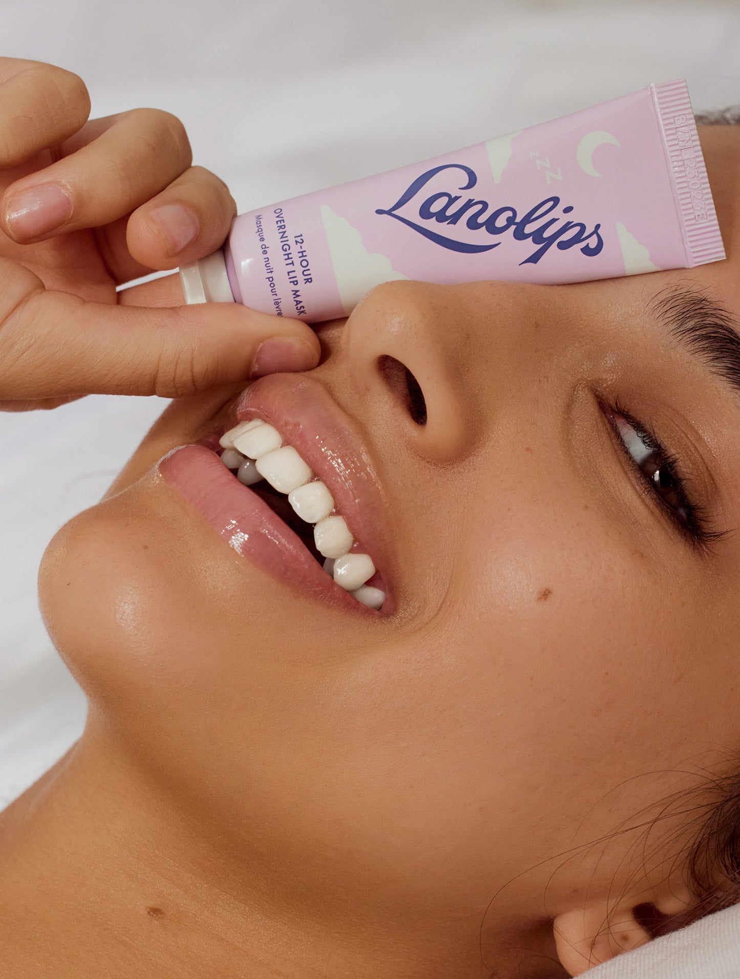 Close up shot of a model covering her eye with the Lanolips 12 Hour Overnight Lip Mask. 