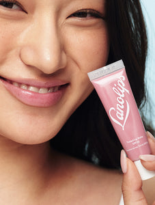 Model holding tube of Lanolips Tinted Lip Balm SPF30 in Rhubarb 