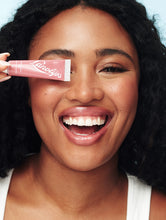 Load image into Gallery viewer, Model smiling and holding Lanolips Tinted Lip Balm SPF 30 in Rhubarb
