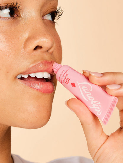 Model applying Lanolips 101 Ointment Multi-Balm in Strawberry to lips, infused with real strawberry extract and vitamin E for sweet, natural hydration. A fruity twist on the iconic Lanolips Original 101 Ointment.