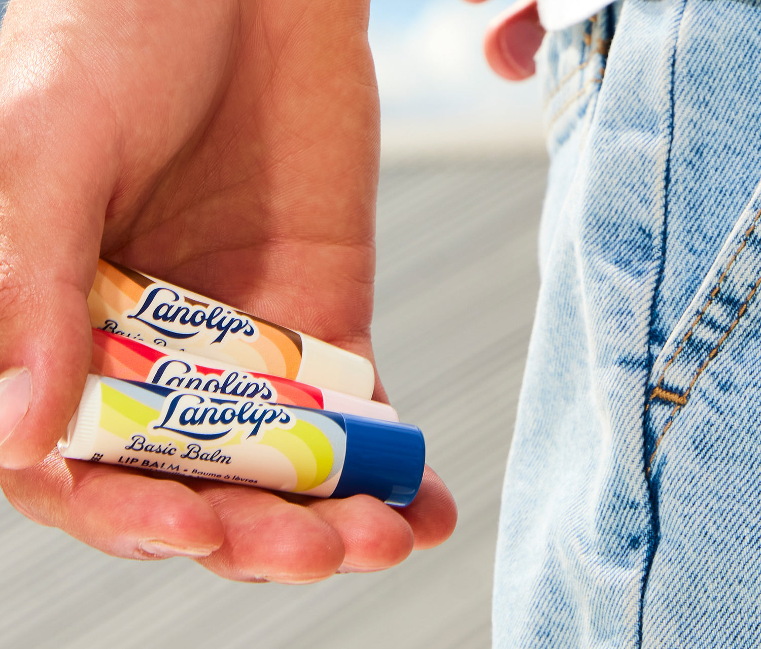 Hand holding the Lanolips Basic Balm range. Comes in three natural flavours: Coconutter, Strawberry and Original Vanilla. 