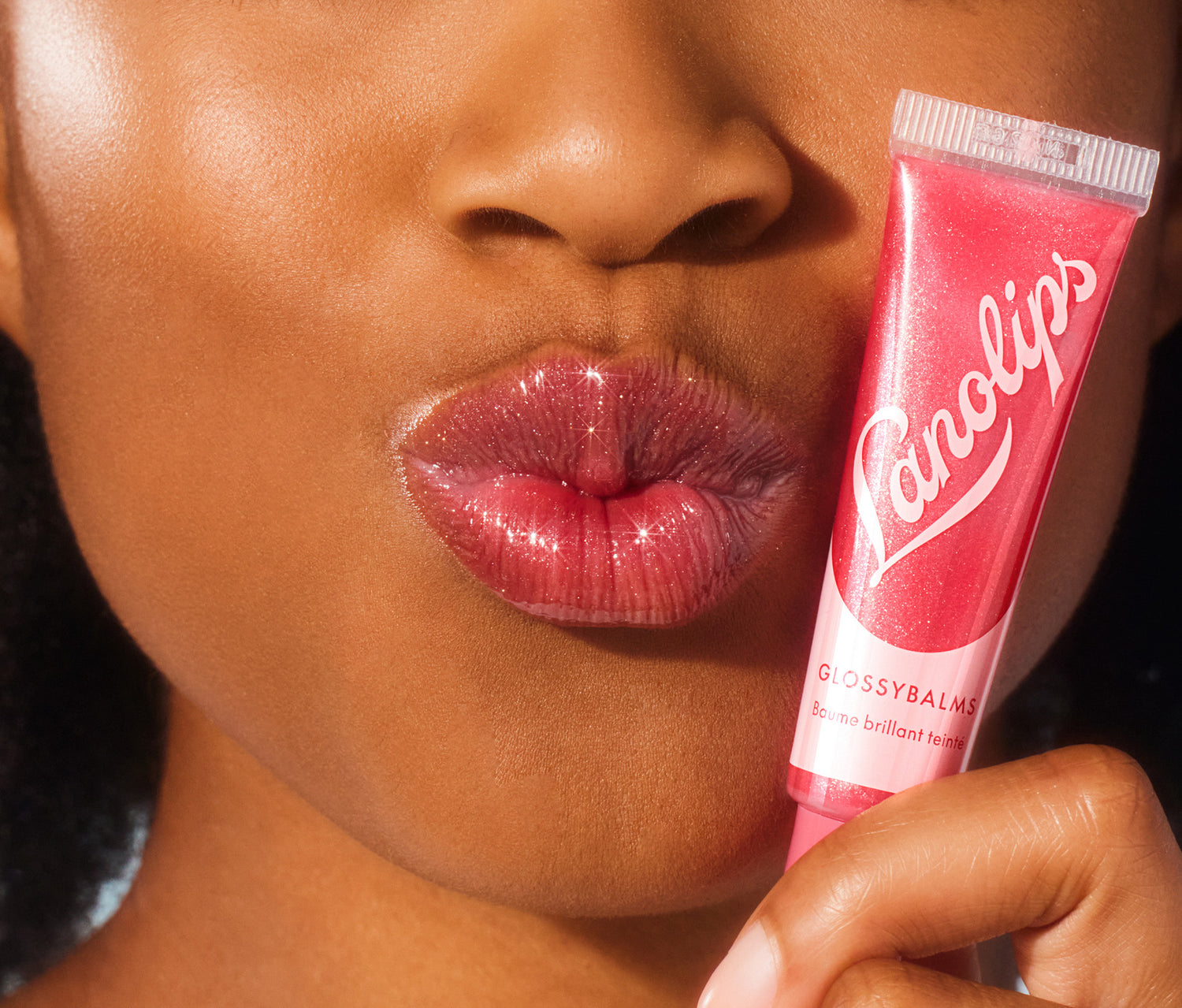 Model holding a lanolips glossy balm candy in her hand.