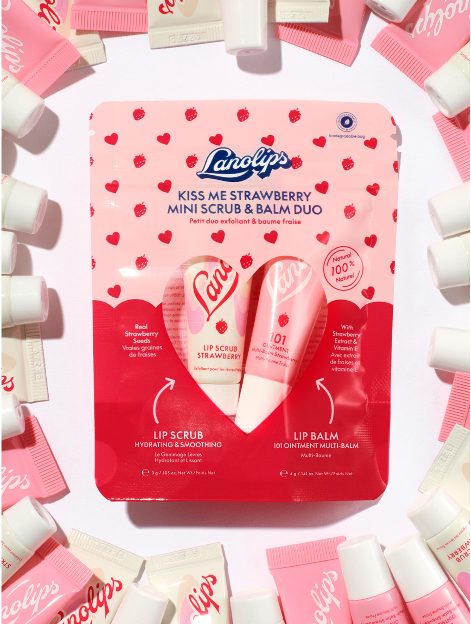 Lanolips Kiss Me Strawberry Mini Scrub & Balm Duo packaging surrounded by product samples on a white background. 