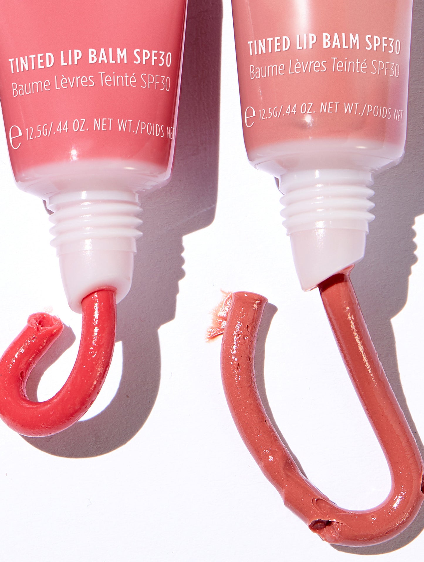 Close up of two Lanolips Tinted Lip Balm SPF30 tubes with curved swatches showing natural pigment. Formulated with hydrating lanolin, vitamin E, and shea butter for soft, nourished lips. The SPF30 protection helps shield against sun damage while providing a natural, dewy finish.
