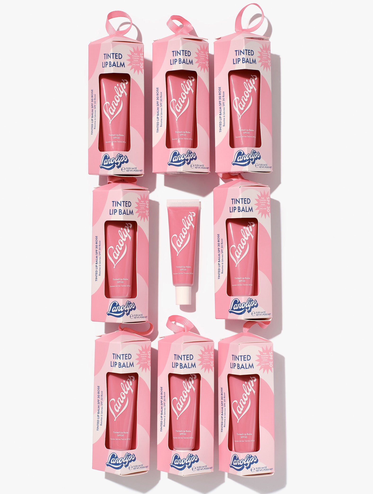 Multiple boxes of Lanolips Tinted Lanolin Lip Balm SPF 30 in Rose on a white background. Now in a bauble for the perfect holiday gift-giving. 