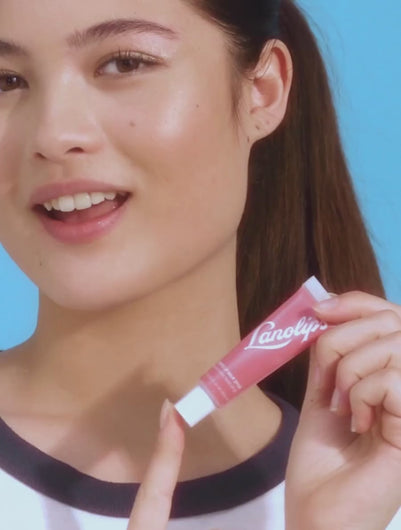 Model applying Lanolips' Tinted Lip Balm in Rhubarb.
