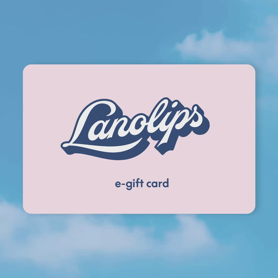 Animated Lanolips e-gift card gently sways against a dreamy blue-sky background with soft clouds. The pastel pink card features the bold Lanolips logo and the words “e-gift card” beneath it,  a perfect digital treat for skincare lovers.