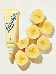Lifestyle shot of Lanolips Banana Balm Lip Sheen 3-in-1 with cut up bananas