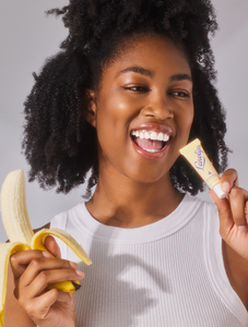 Model wearing Lanolips Banana Balm Lip Sheen 3-in-1,  a whipped banana & lanolin lip sheen, for juicy, glowing lips. 
